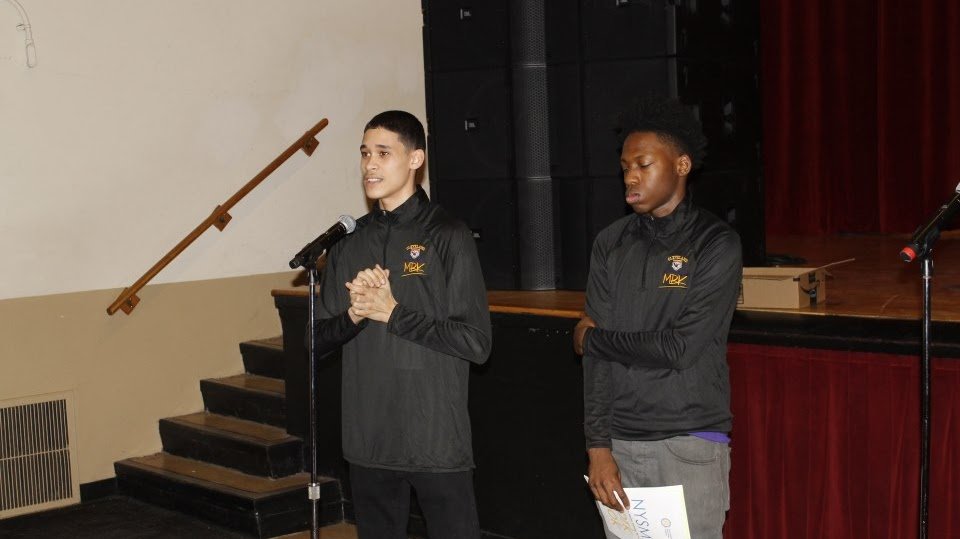 Two black high school students standing and delivering a presentation